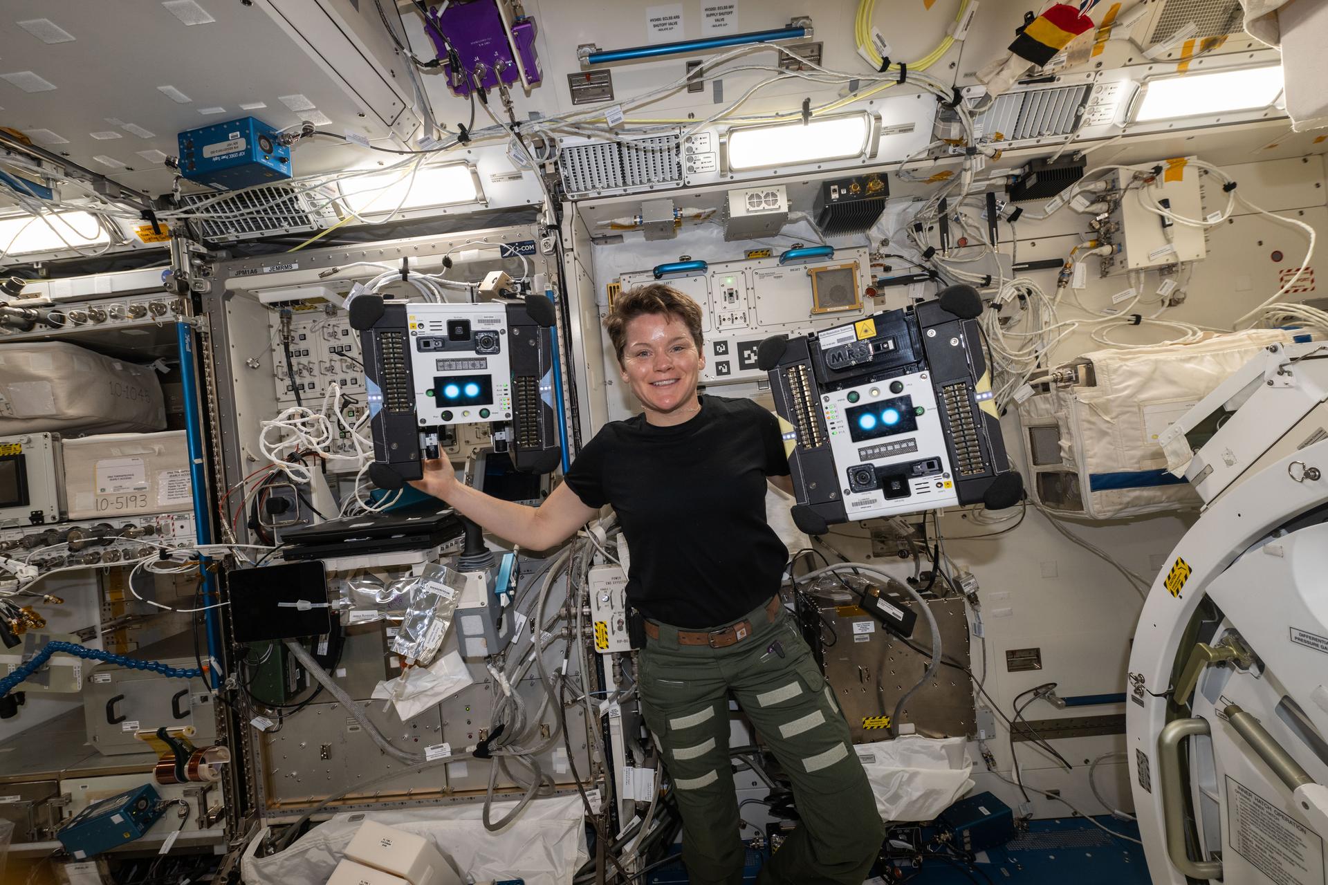 NASA astronaut McClain poses with Astrobee robots Bumble and Honey.